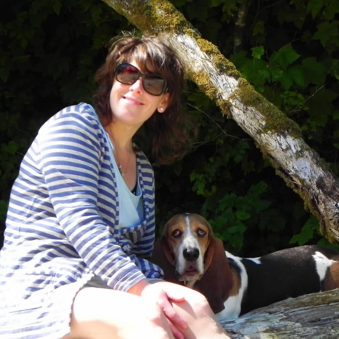 A person sitting outdoors beside a Basset Hound